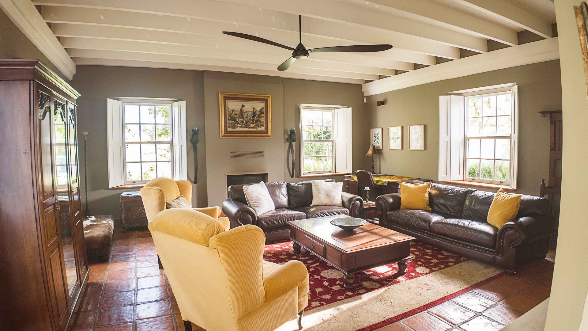 Spacious lounge with beamed ceilings, leather sofas and mustard accents