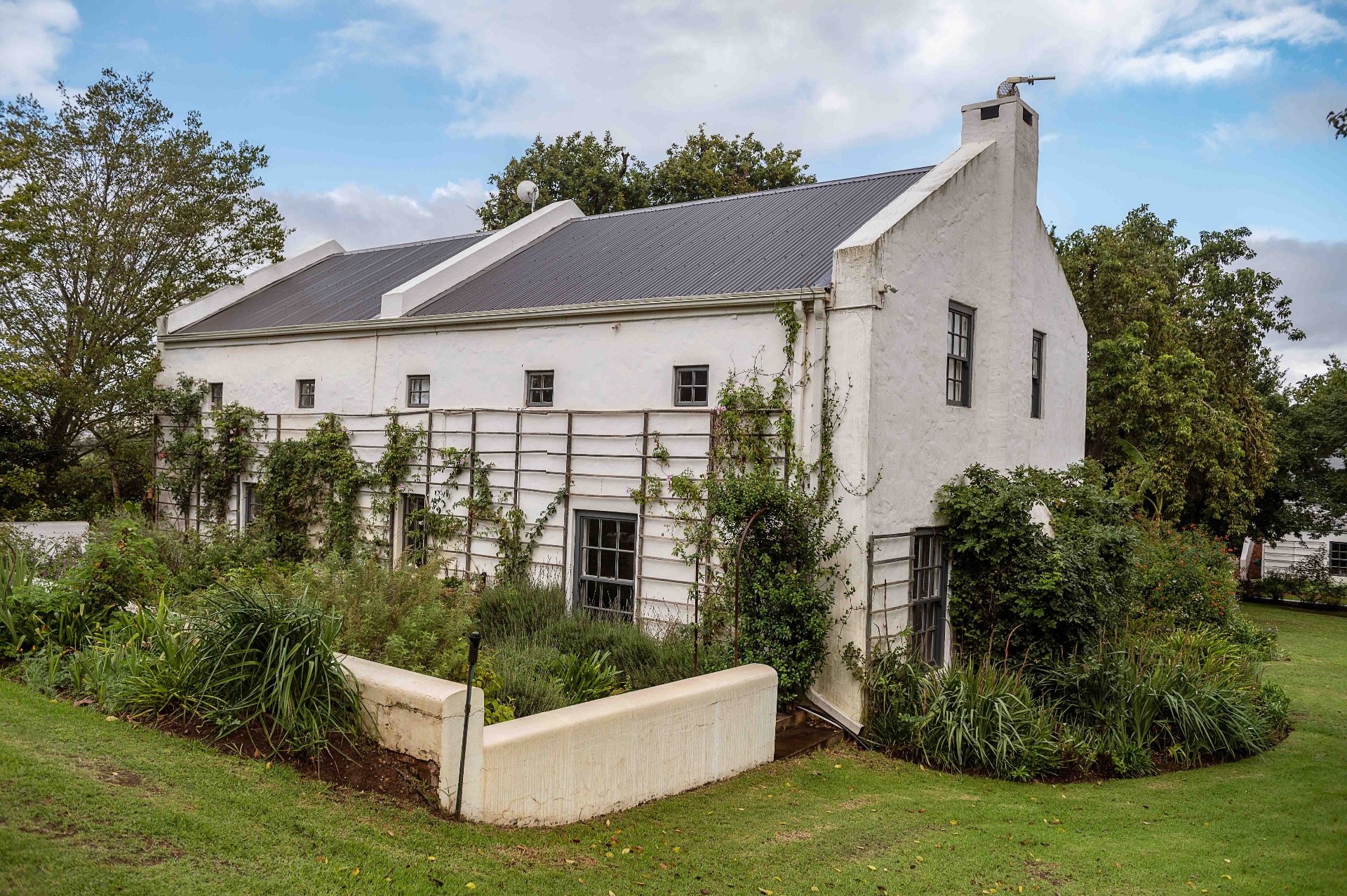 Ou Meul cottage exterior with gabled chimney and trellised vines