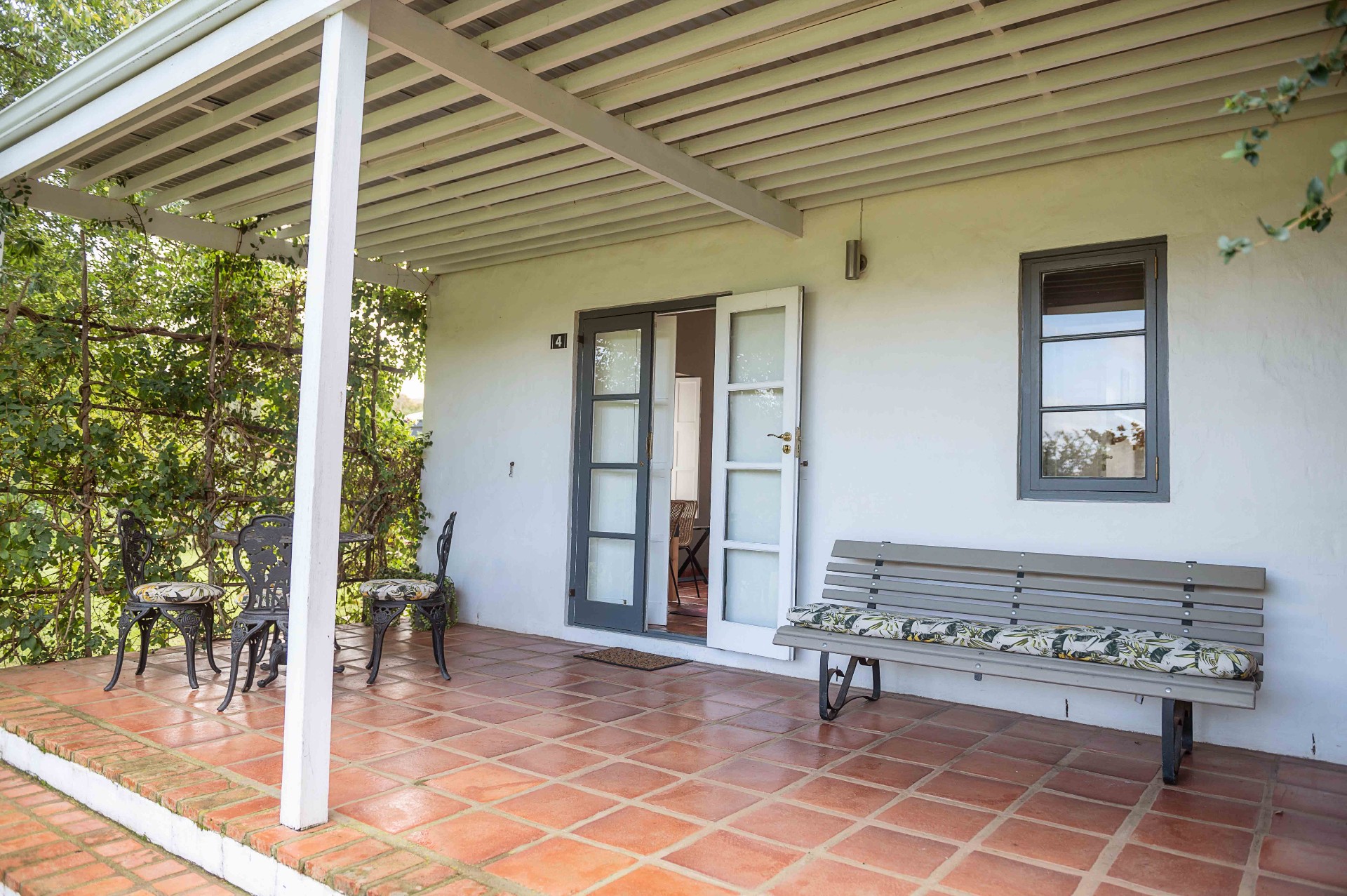Covered patio of guest room 4 with bench and bistro set