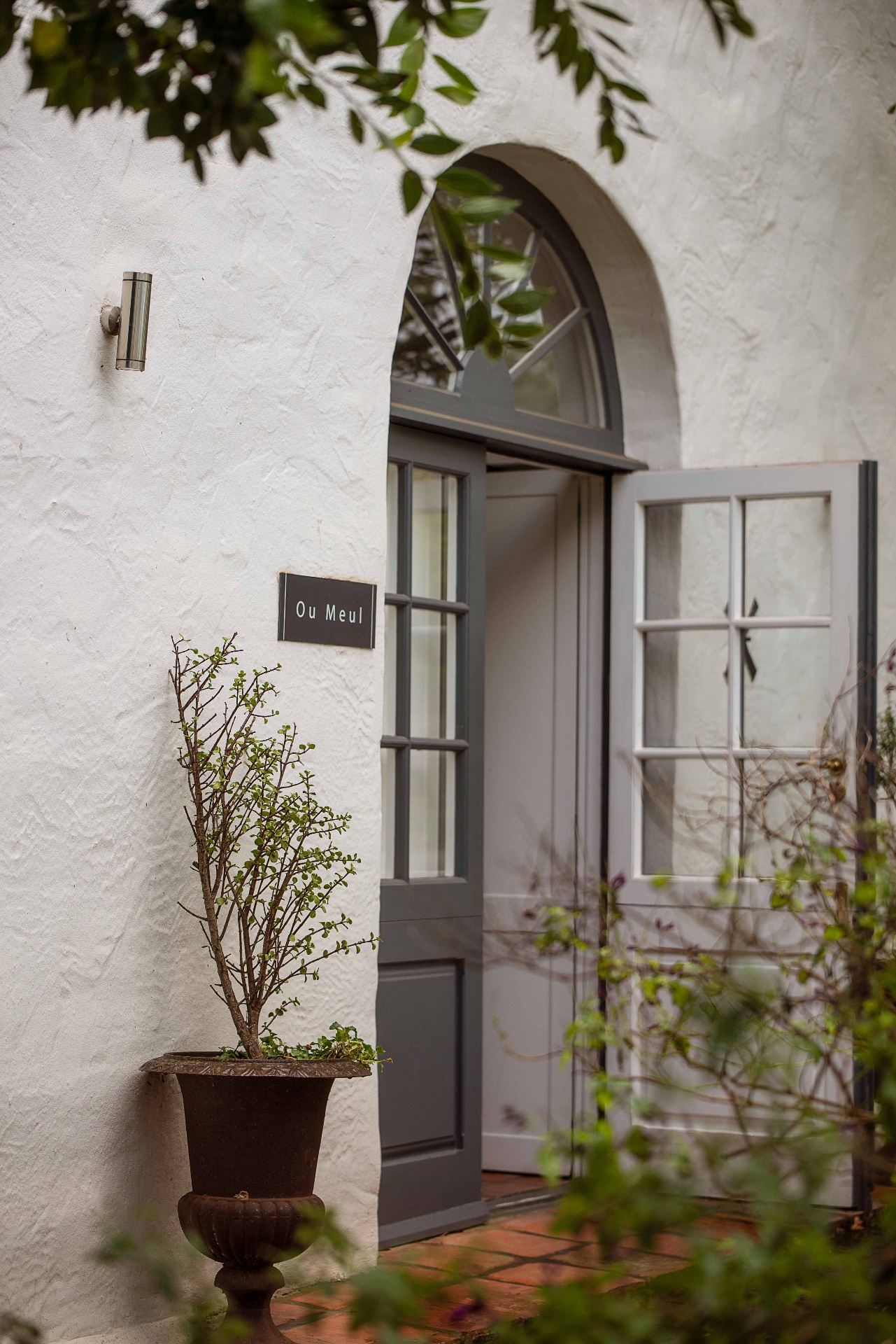 Arched front door of Ou Meul with planted urn
