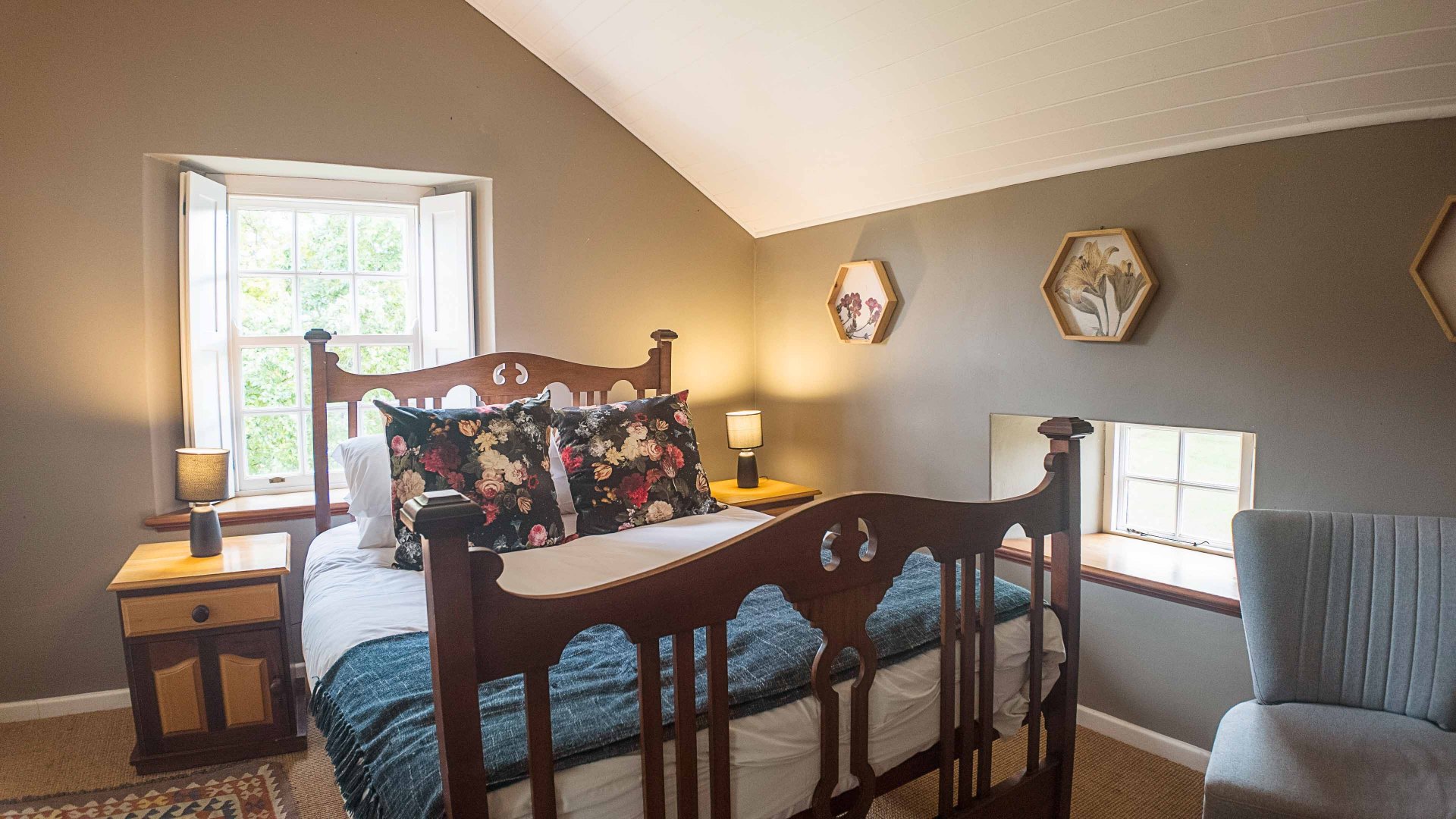 Cosy bedroom with carved wooden bedstead and garden window