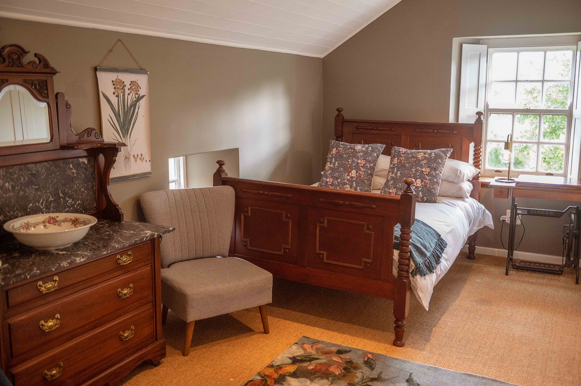 Bedroom with antique wooden bed, dresser and floral pillows