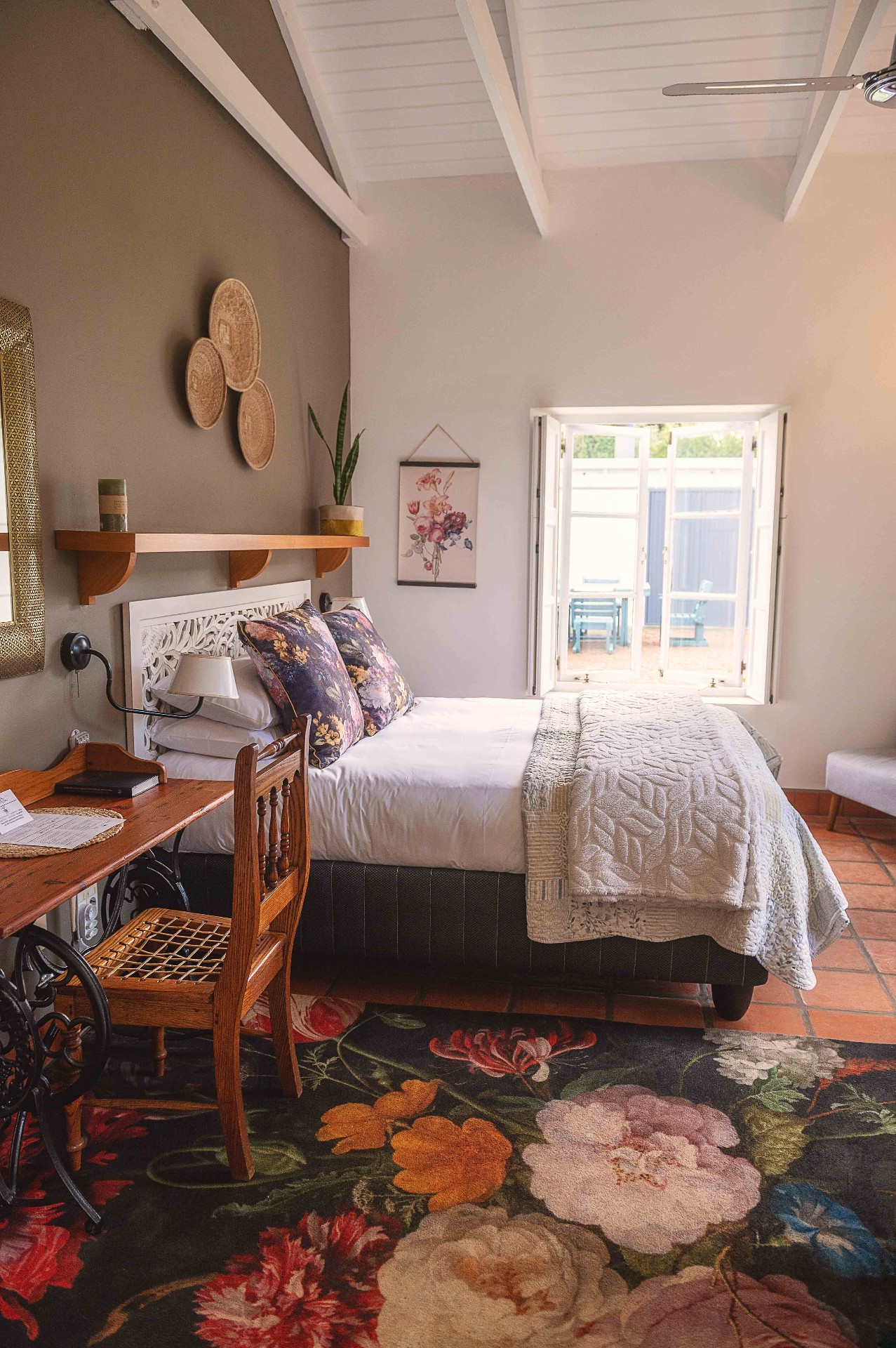 Cosy bedroom with floral rug and antique writing desk