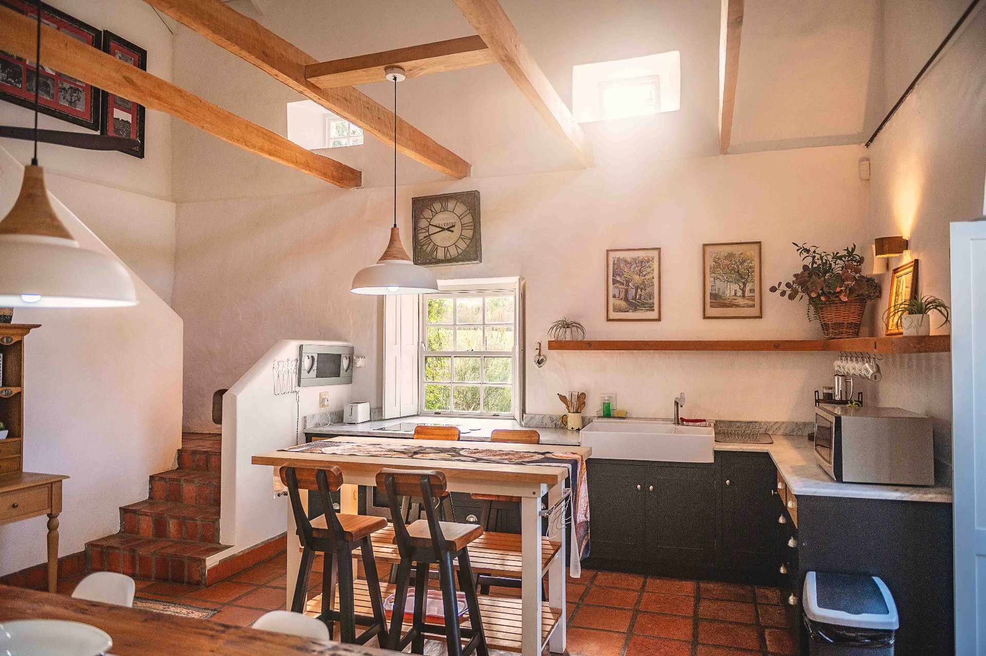 Country kitchen with timber beams, pendant lights and terracotta floors